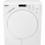 En vit Miele Novotronic T 764C frontmatad torktumlare med rund dörr, kontrollpanel med knappar och digital display samt olika torkalternativ märkta på framsidan.