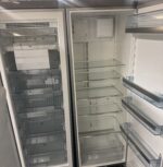 Två öppna, tomma kylskåp står bredvid varandra och visar hyllor av klart glas, genomskinliga dörrfack och inga livsmedel eller föremål inuti. Insidan är ren och väl upplyst.